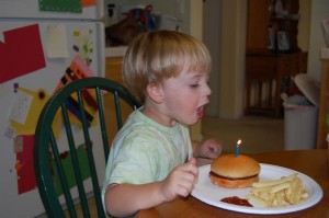 Caden blowing out his cheeseburger candle